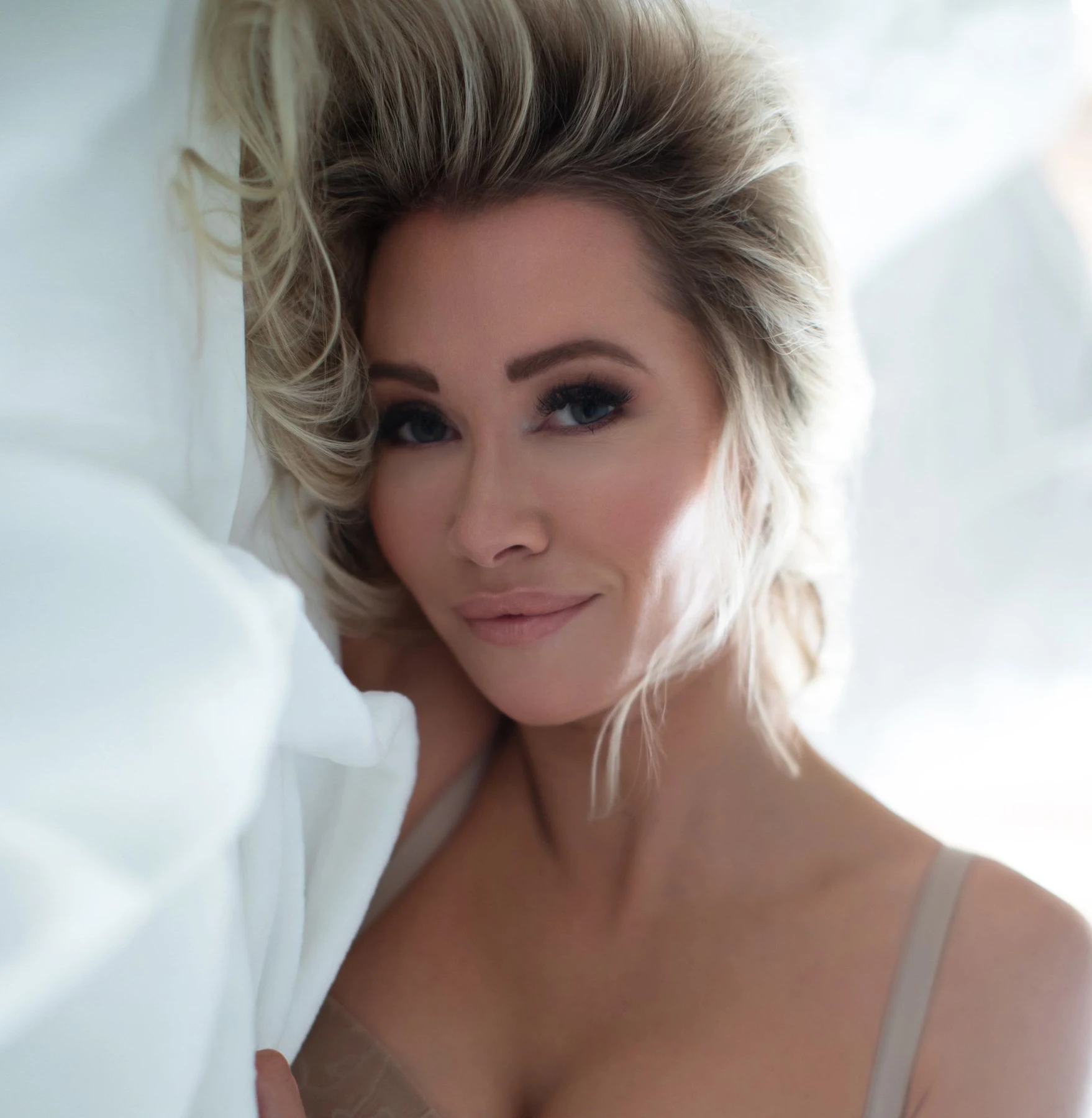 Featured beauty retouching of a blonde woman resting on white bedding
